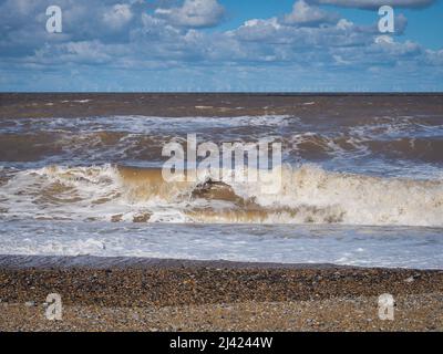 Waves crash onto beach with wind farm on the horizon, Blakeney Point, Norfolk Stock Photo