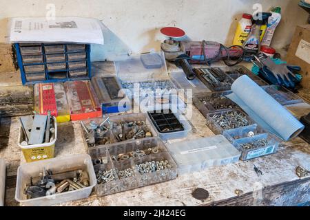 Number of nuts, bolts, washers, rivets, springs and other parts organised in plastic boxes on the bench of a workshop. Stock Photo