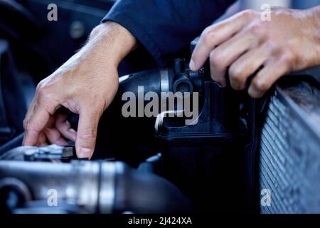 Hes hands on. Cropped shot of an unrecognizable male mechanic working on the engine of a car during a service. Stock Photo