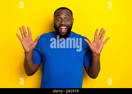 Portrait of attractive impressed cheerful guy showing palms having fun isolated over bright yellow color background Stock Photo
