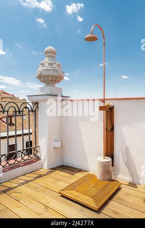 Copper and wood shower on a terrace of a vintage penthouse apartment with wooden floors and metal railings and baroque decorations Stock Photo