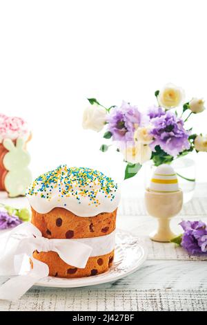 Traditional Easter sweet bread or cakes with white icing and sugar decor and quail eggs over white wooden table. Various Spring Easter cakes. Happy Ea Stock Photo