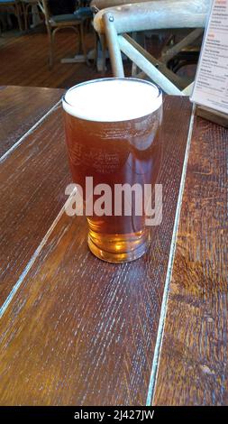 WINDERMERE. CUMBRIA. ENGLAND. 03-26-22. A pint of beer on a table top in a Lake District pub. Stock Photo