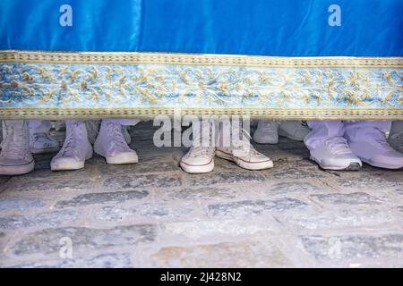 White shoes of the costalero bearers under the platform of the virgin doing the turning maneuver down a city street in a procession of holy week. This Stock Photo