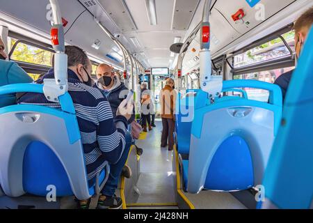 Huelva, Spain - April 9, 2022: Crowds of people inside a bus. Interior view of a municipal bus with passengers wearing protective mask and different p Stock Photo