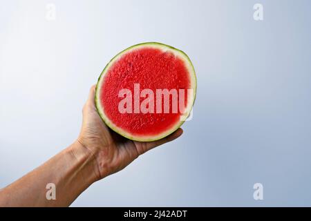 Small seedless watermelon on hand in a bright background Stock Photo