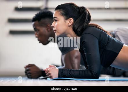 Where strong bodies begin. Shot of a young man and woman doing plank exercises in a gym. Stock Photo