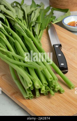 Fresh raw green water spinach,  kangkong, on a wooden cutting board close up Stock Photo