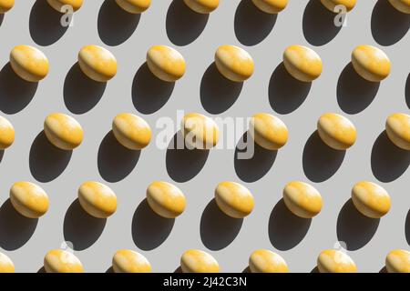 Repeating painted yellow eggs with a hard shadow on a gray background, Easter background in pop art style, seamless pattern with Easter eggs, Stock Photo