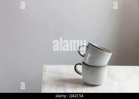 A pyramid of white cups on a beige table in the kitchen. Scandinavian style. Place for your text. Copy space Stock Photo