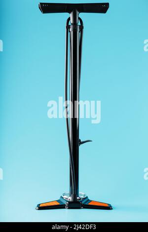 Black bicycle manual air pump for pumping wheels on a blue background with a vertical composition Stock Photo