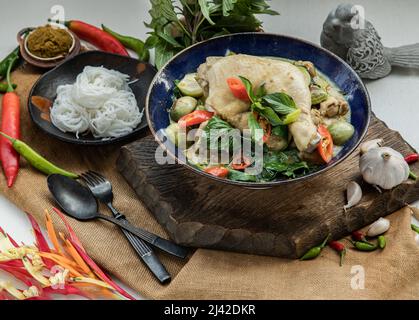 Green curry with Chicken and Green-white varieties of Thai eggplants (Kaeng khiao wan) in Ceramic bowl served with Thai rice noodles (Fermented rice f Stock Photo