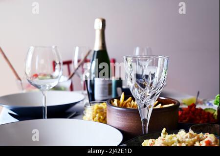 unopened bottle of wine, empty wineglasses and side dishes on the table Stock Photo