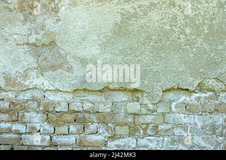 Gray plastered old brickwall with chipped stucco pieces. Grunge white brick wall with damaged surface background Stock Photo