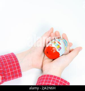 Moscow, Russia - April 1, 2022:: Kinder Surprise , tasty chocolate egg in hands on white easter time Stock Photo