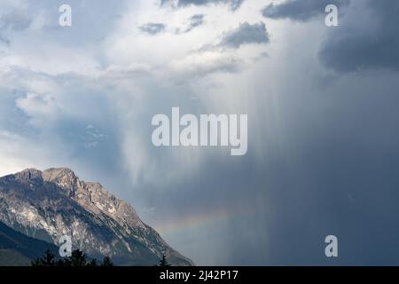 A rainbow forms over a mountain flank after a heavy thunderstorm Stock Photo