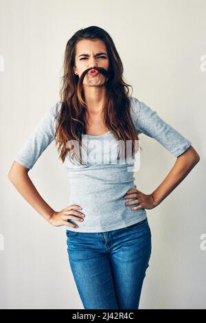 Do you like me now. Studio shot of an attractive young woman posing against a grey background. Stock Photo