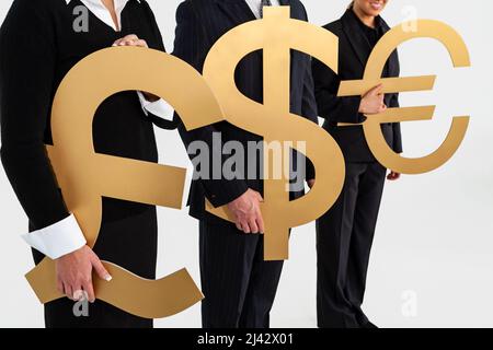 Anonymous business people team, businessman and businesswomen, holding large gold money currency symbols, British Pound, Dollar and Euro. Exchange rat Stock Photo