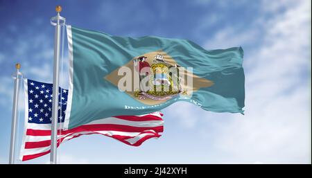 The Delaware state flag waving along with the national flag of the United States of America. In the background there is a clear sky. Stock Photo