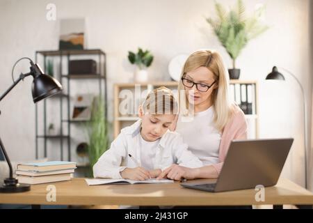Mother helping his son with his homework at home. Social distancing and self isolation in quarantine lockdown for Coronavirus Covid19 Stock Photo