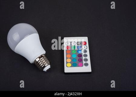 Multi color led bulb with a remote control on a black background Stock Photo