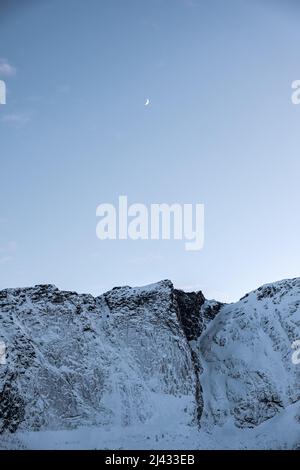 Snowy mountain and crescent moon in blue sky at scandinavia region Stock Photo