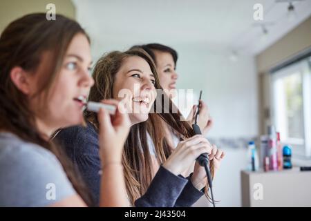 Feeling pretty. Cropped shot of three young friends putting on makeup and styling their hair in the bathroom. Stock Photo