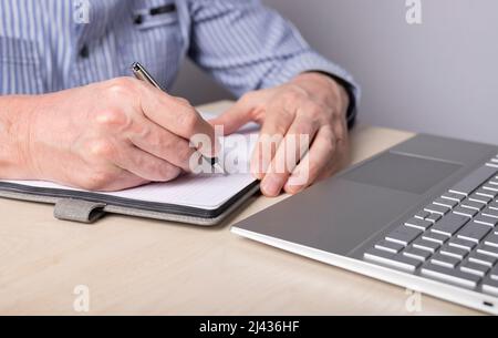 Male hands close up, taking notes in planner, writing in notebook. Stock Photo