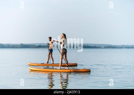 young couple in love standing on their sapboards and holding each other's hands. Stock Photo