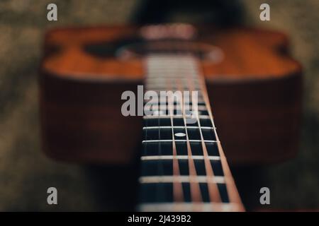 Looking down the neck of an acoustic guitar focused on the fretboard, fret and position marker with a blurred background Stock Photo