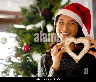 Christmas isnt just a day, its a frame of mind. Shot of a young woman holding Christmas decor at home. Stock Photo