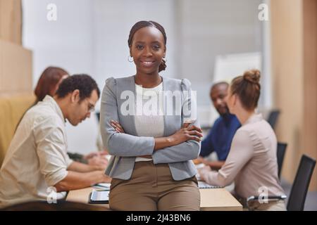 With this team behind me, its easy to be confident. Cropped portrait of an attractive young businesswoman standing with her arms folded in the Stock Photo