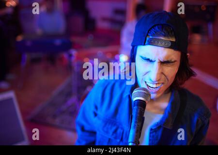 Portrait of music artist singing passionately to microphone in live performance, copy space Stock Photo
