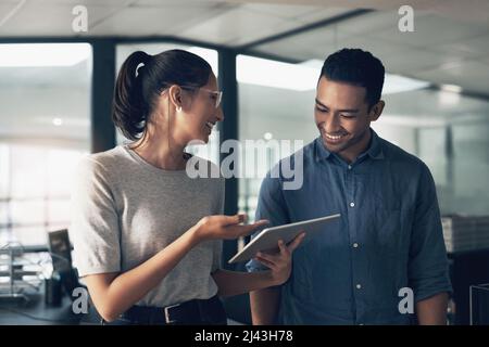 Love is for kids. Compatibility is for adults. Shot of two young workers using a digital tablet in a modern office. Stock Photo