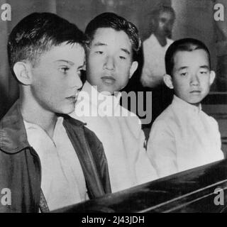 MacArthur's Son Meets Japanese Princes -- Arthur MacArthur (left), 11-year-old son ***** General Douglas MacArthur, sits with the eldest and youngest sons of Emperor Hirohito at an inter-collegiate swimming meet in Tokyo, September 15. In center is Crown Prince Akihito, 15. At right is Prince Masahito, 13. It was the first time that the son of the U.S. supreme commander in Japan had met the sons of the emperor. September 19, 1949. (Photo by AP Wirephoto). Stock Photo