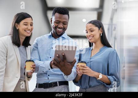 They encourage me, share ideas, and get me motivated. Shot of three businesspeople discussing something on a digital tablet. Stock Photo