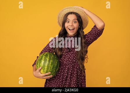 amazed kid holding fresh ripe water melon fruit in summer straw hat, nutrition Stock Photo