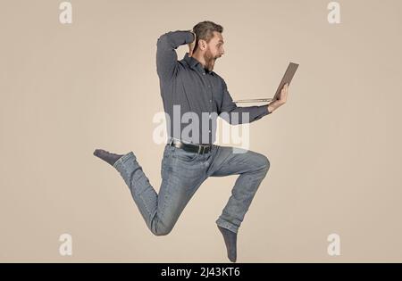 surprised energetic man jumping while working online on laptop hurry up for shopping, surprise. Stock Photo