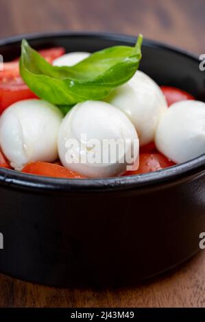 Italian food, tasty caprese salad with red cherry tomatoes, white mozzarella cheese and green basil leaves Stock Photo