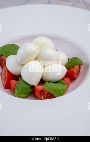 Italian food, tasty caprese salad with red cherry tomatoes, white mozzarella cheese and green basil leaves Stock Photo