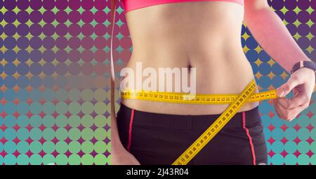 Mid section of caucasian fit woman measuring her waist against colorful background with copy space Stock Photo
