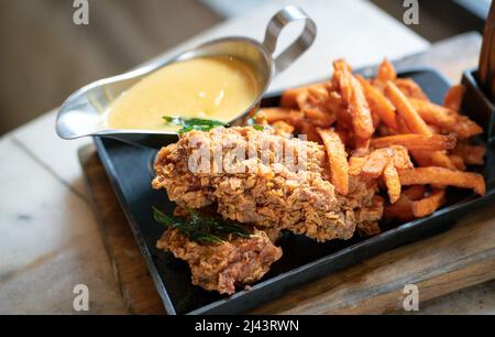 Chicken chop with chips and salted egg sauce on a grill pan. Stock Photo