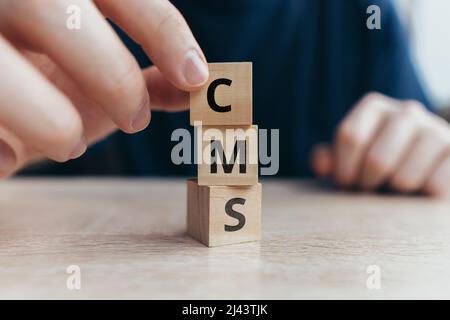 Acronym CMS or Content Management System. Text on wooden cubes. Stock Photo