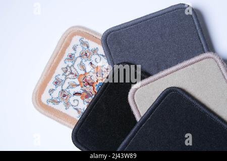 Carpet. Floor covering samples. Multi-colored rug with stitched edges. Close-up on a white background. Stock Photo