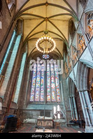 Low angle view of majestic,colorful ornate windows,and hanging ceiling lightis,overlooking the isle and memorial tombs inside the cathedral church of Stock Photo