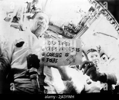 Astronauts Walter Schirra (on right), mission commander; and Donn Eisele, command module pilot; are seen in the first live television transmission from space. Schirra is holding a sign which reads, 'Keep those cards and letters coming in, folks!' Stock Photo