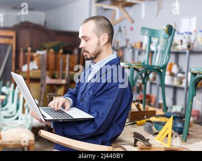 Carpenter using laptop in workshop Stock Photo