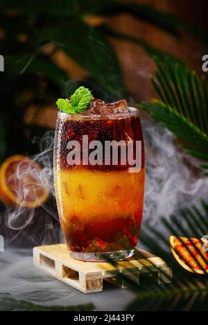 Bumble coffee with ice on a dark tropical background. Espresso, orange juice and syrup in layers Stock Photo