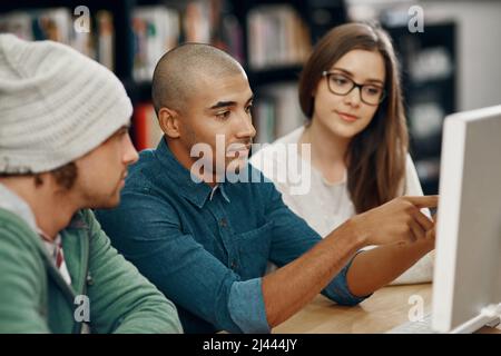 Studying with friends has its benefits. Cropped shot of three young university students studying in the library. Stock Photo