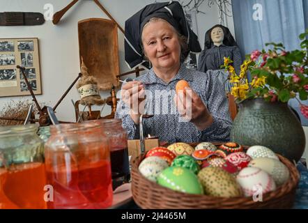 Dissen, Germany. 05th Apr, 2022. Babette Zenker, director of the Lower Sorbian Museum of Local History in Dissen, wears a Sorbian-Wendish working costume and decorates Easter eggs using the wax batik technique. (to dpa With quill and wax: Easter egg painting in Sorbian) Credit: Patrick Pleul/dpa/Ģ����ý Live News Stock Photo